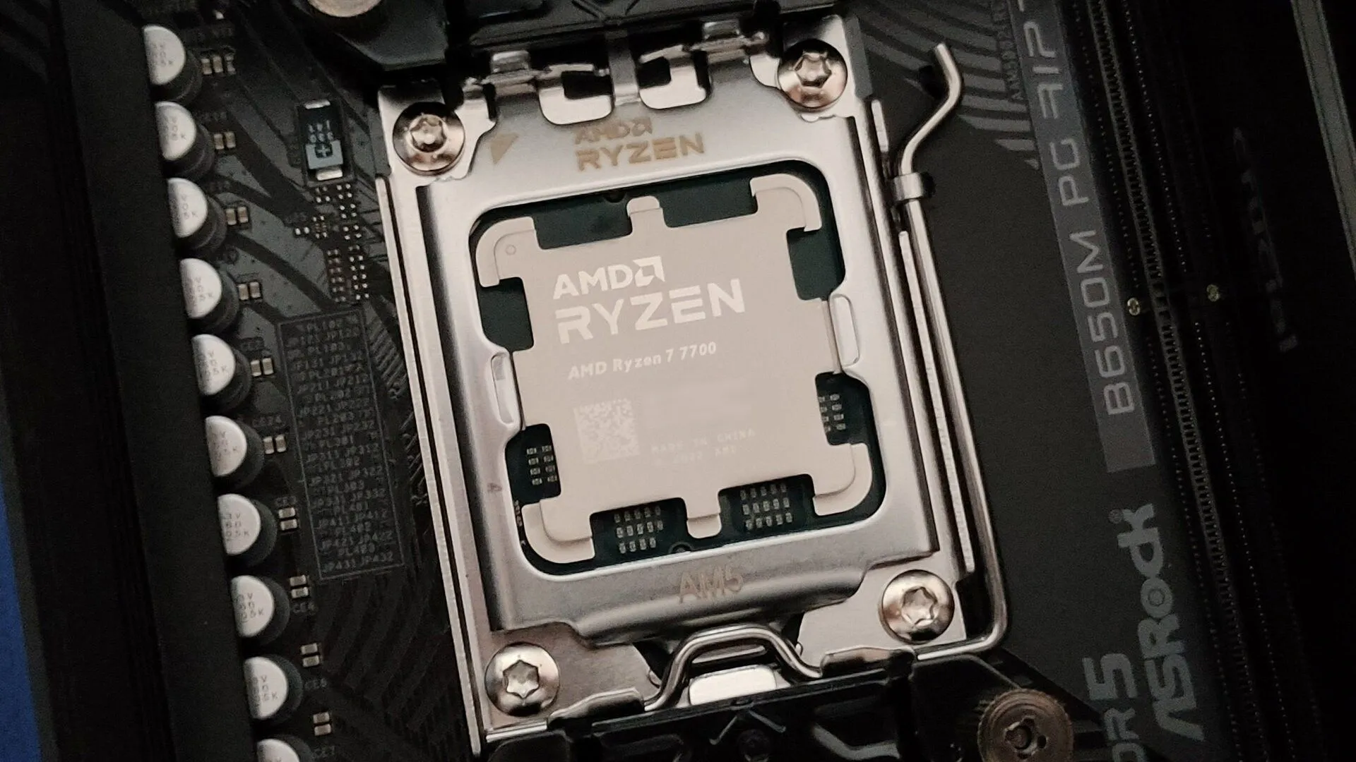 Ảnh cận cảnh CPU AMD Ryzen 7 7700 gắn trên socket AM5 của bo mạch chủ ASRock B650M PG Riptide, đại diện cho hệ thống PC hiện đại.