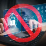 Bàn tay gõ trên laptop với biểu tượng cấm đỏ phủ lên các icon bảo mật, minh họa sự hạn chế truy cập kỹ thuật số do không dùng trình quản lý mật khẩu.