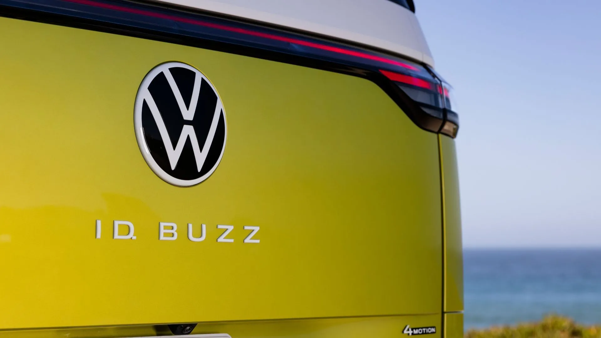 Biểu tượng Volkswagen và tên xe ID. Buzz ở cửa sau của xe điện màu vàng.