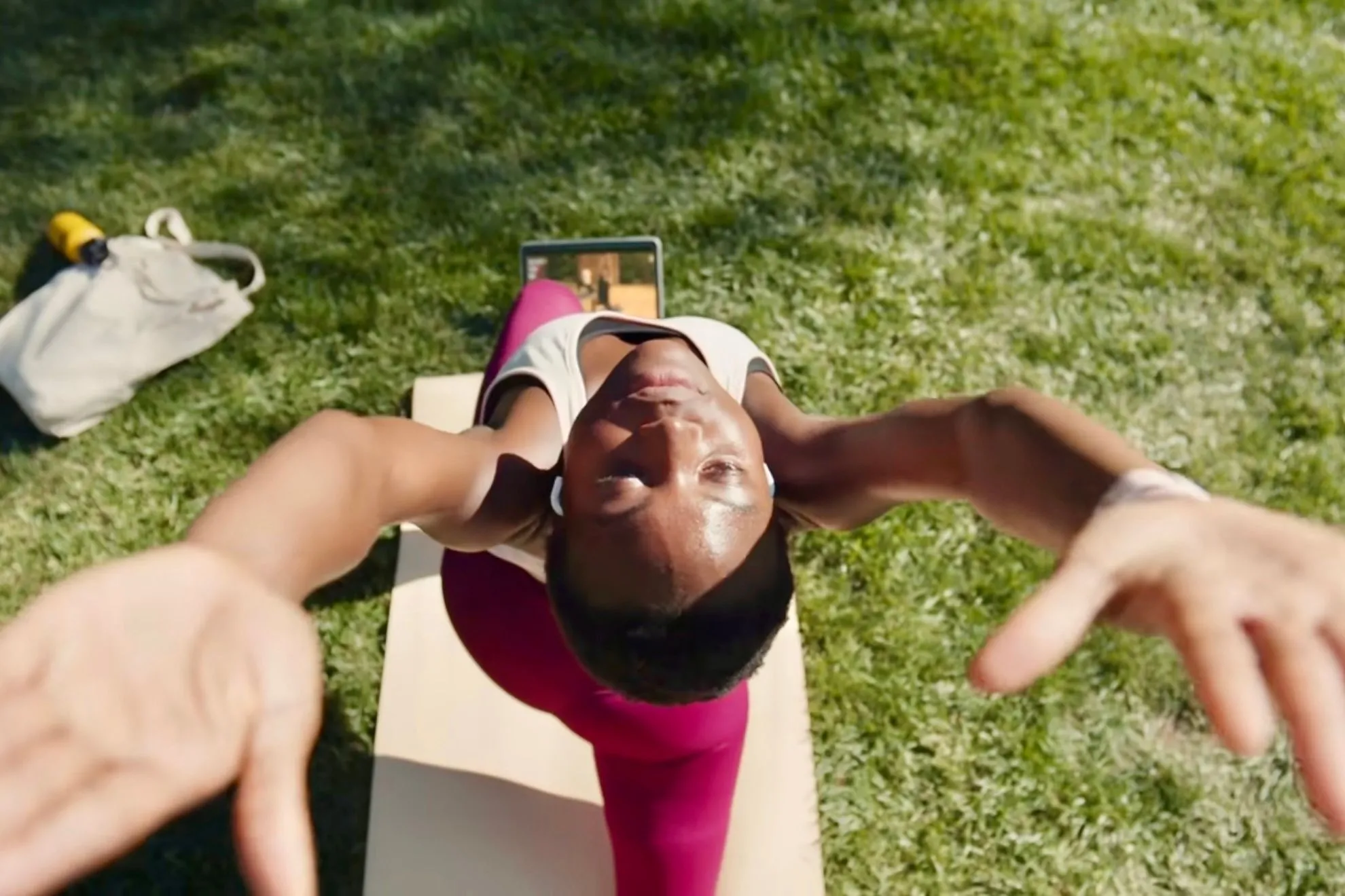 Cá nhân tập yoga ngoài trời với Apple Fitness+ trên iPad trong công viên