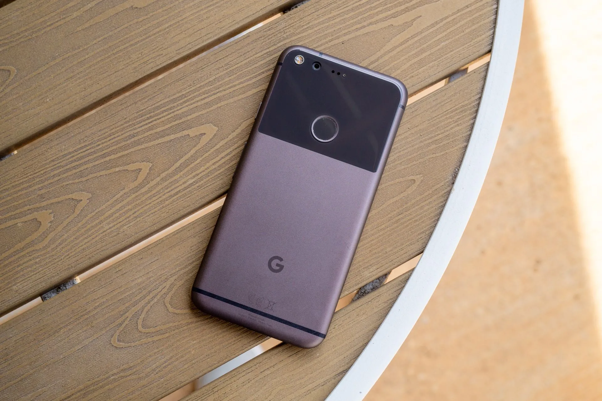 Điện thoại Google Pixel thế hệ đầu tiên màu đen đặt trên bàn, với thiết kế nhôm kính đặc trưng và cụm camera đơn
