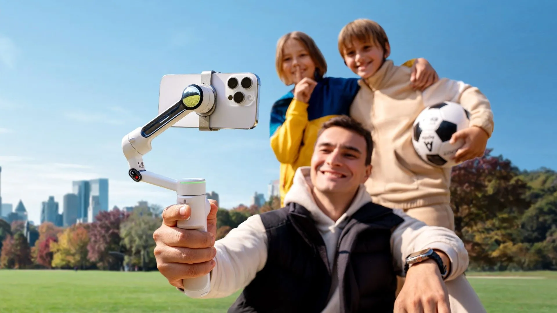 Insta360 Flow 2 Pro đang theo dõi và quay phim những người đi bộ đường dài chụp ảnh gia đình với quả bóng đá trên triền đồi