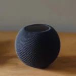 Loa HomePod Mini màu đen đặt trên bàn gỗ, minh họa cho việc phát nhạc qua Phím tắt.