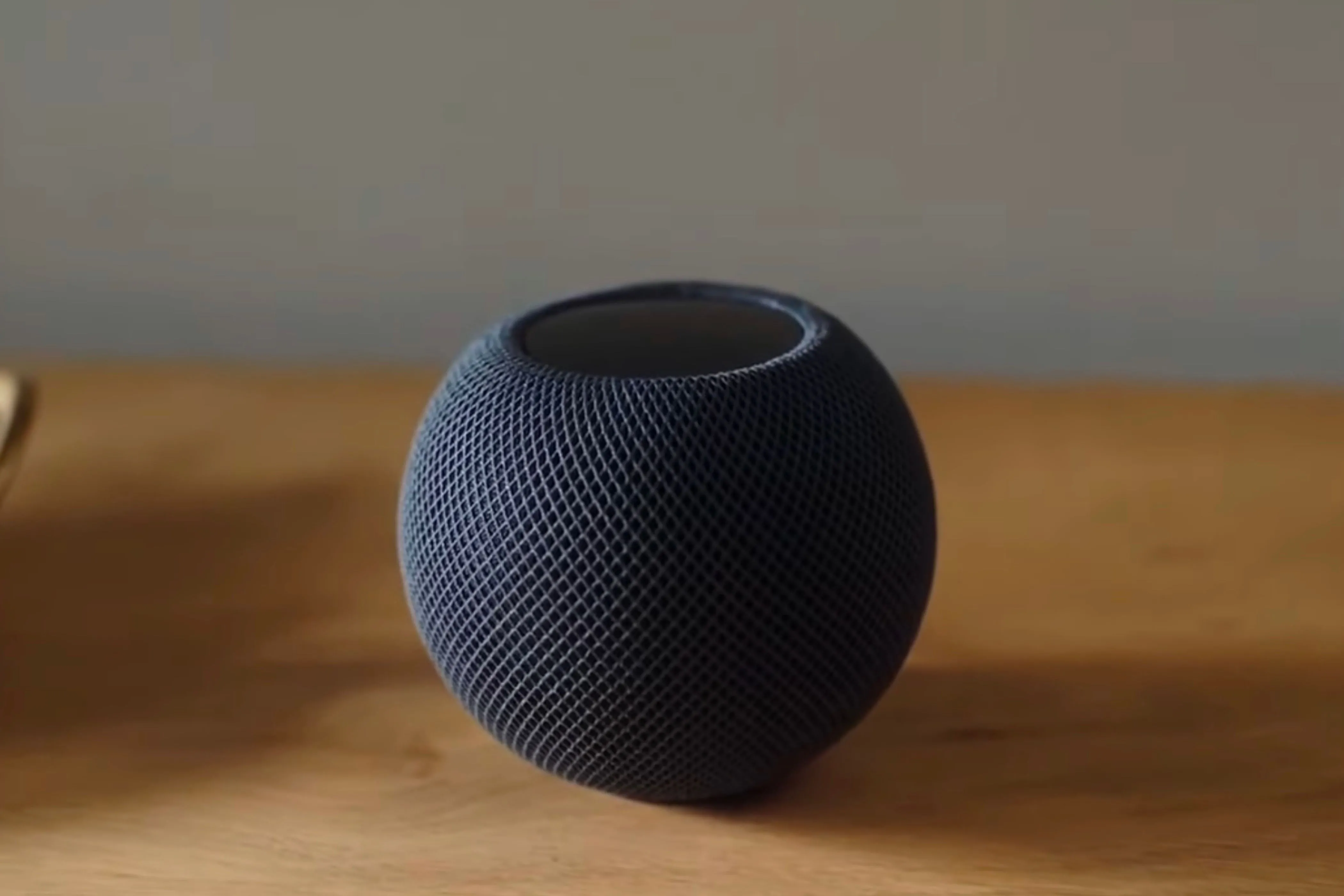 Loa HomePod Mini màu đen đặt trên bàn gỗ, minh họa cho việc phát nhạc qua Phím tắt.