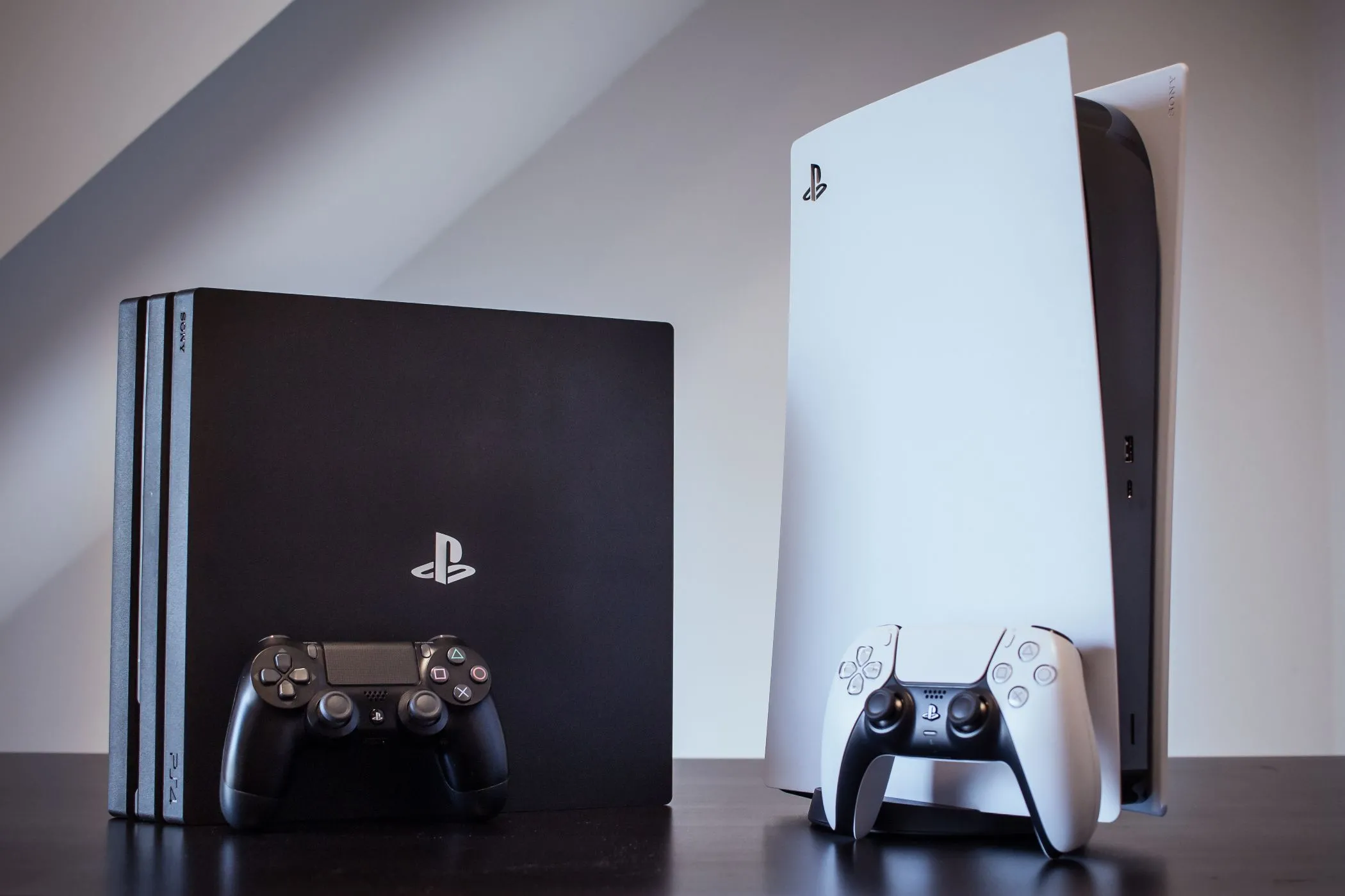 Máy chơi game PlayStation 4 Pro và PlayStation 5 đặt cạnh nhau, minh họa sự tương đồng về thiết kế và đồ họa giữa các thế hệ console gần đây