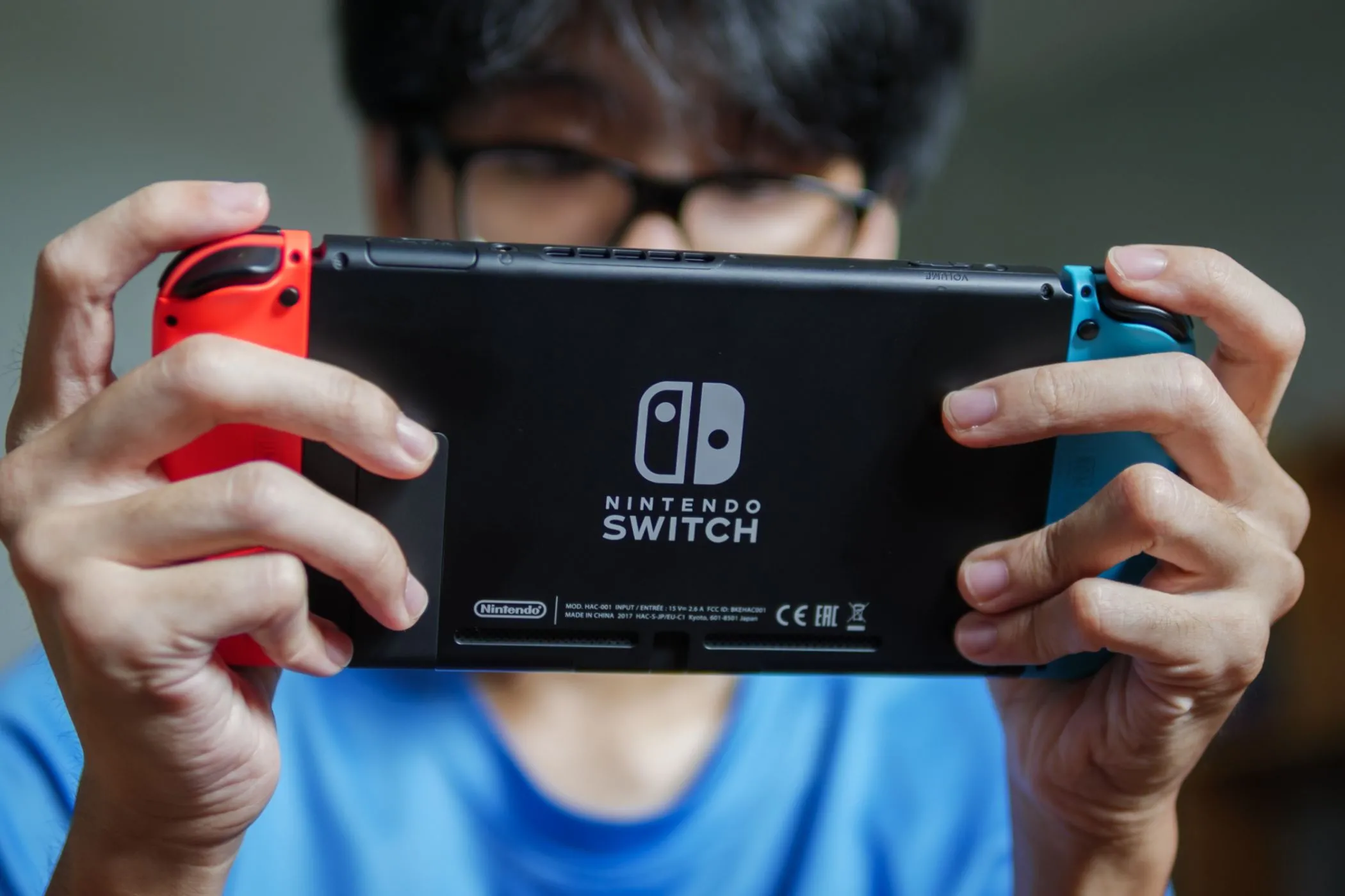 Một người đàn ông đang chơi game trên máy Nintendo Switch cầm tay, tận dụng thời gian rảnh khi đi du lịch.