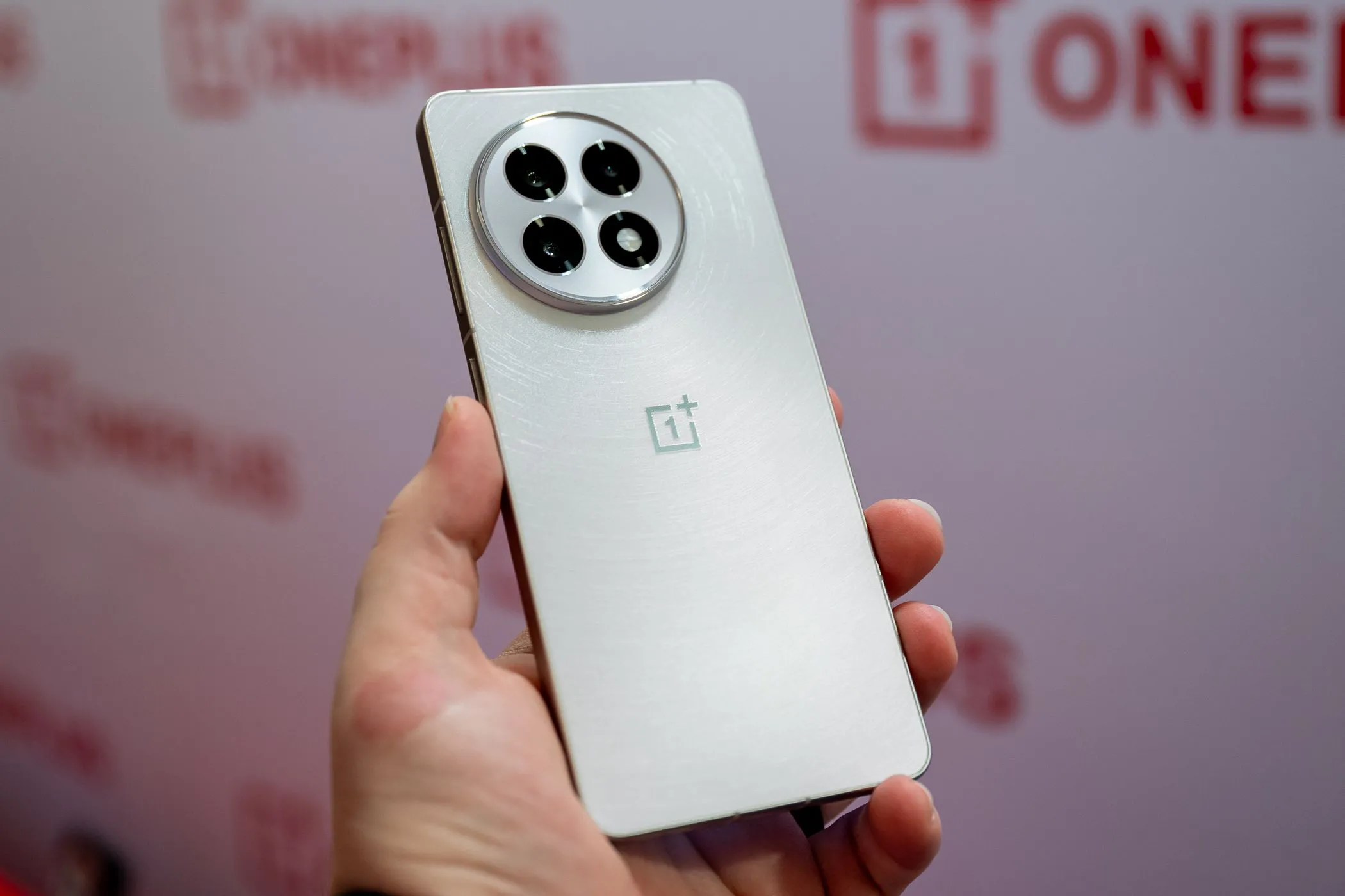 Người đang cầm chiếc điện thoại OnePlus 13R màu trắng