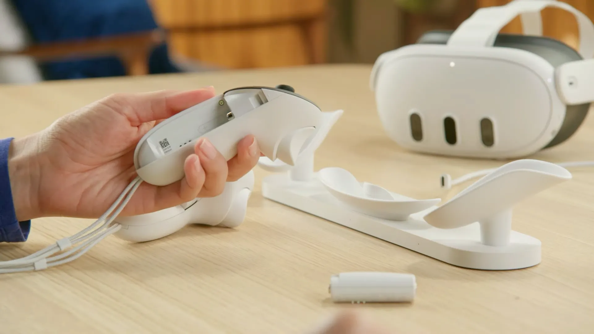 Người dùng cầm bộ điều khiển Meta Quest 3 Touch Plus với pin sạc, dock sạc và kính Meta Quest 3
