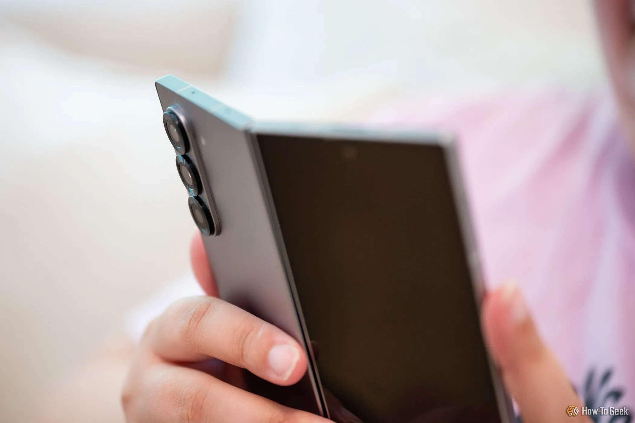 Người dùng cầm Samsung Galaxy Z Fold 6 mở hé, nhìn vào cụm camera sau