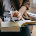 Người dùng đang đọc một cuốn sách giấy thay vì sách điện tử trên điện thoại.