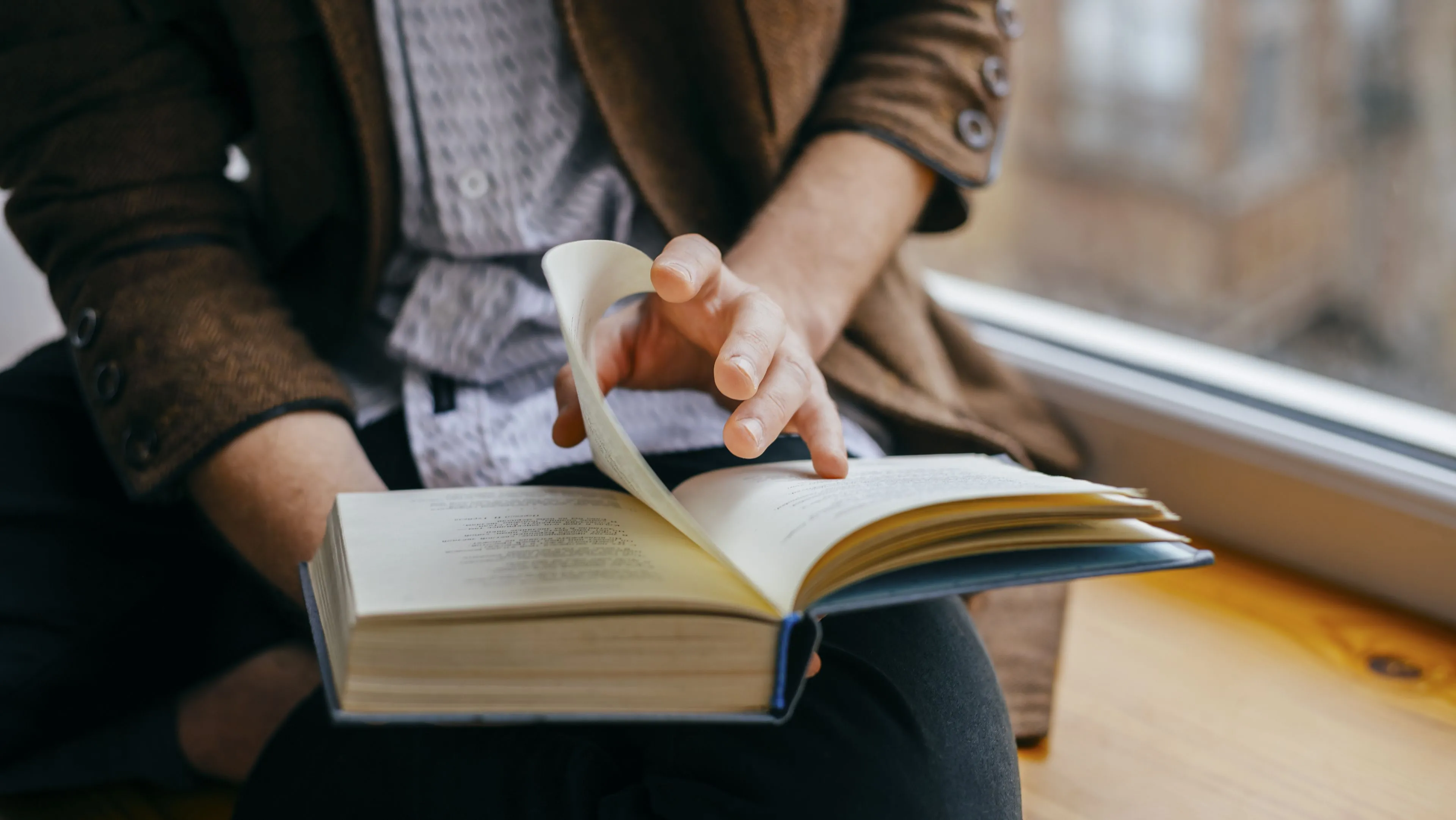 Người dùng đang đọc một cuốn sách giấy thay vì sách điện tử trên điện thoại.
