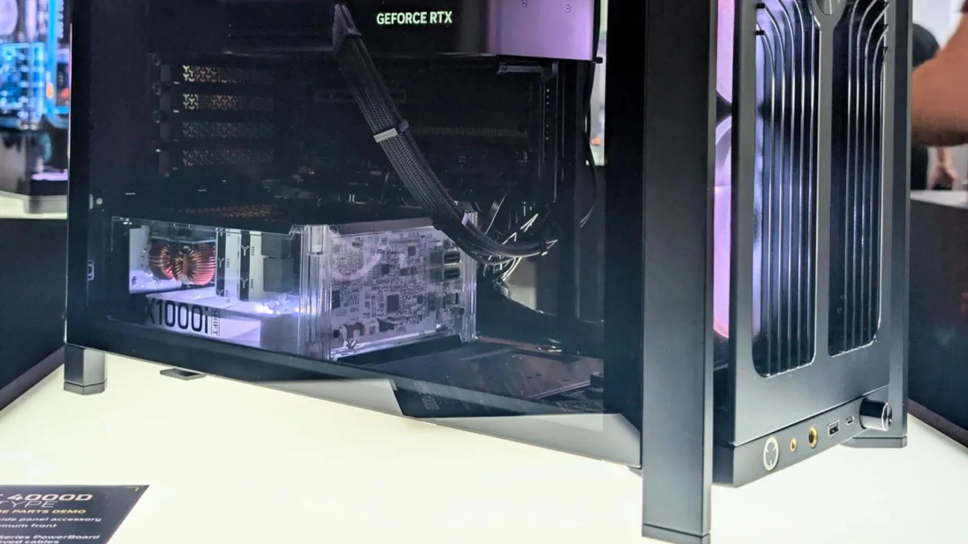 Nguồn máy tính Corsair HX1000i SHIFT prototype trong suốt được gắn bên trong một thùng máy PC, khoe rõ các linh kiện bên trong.